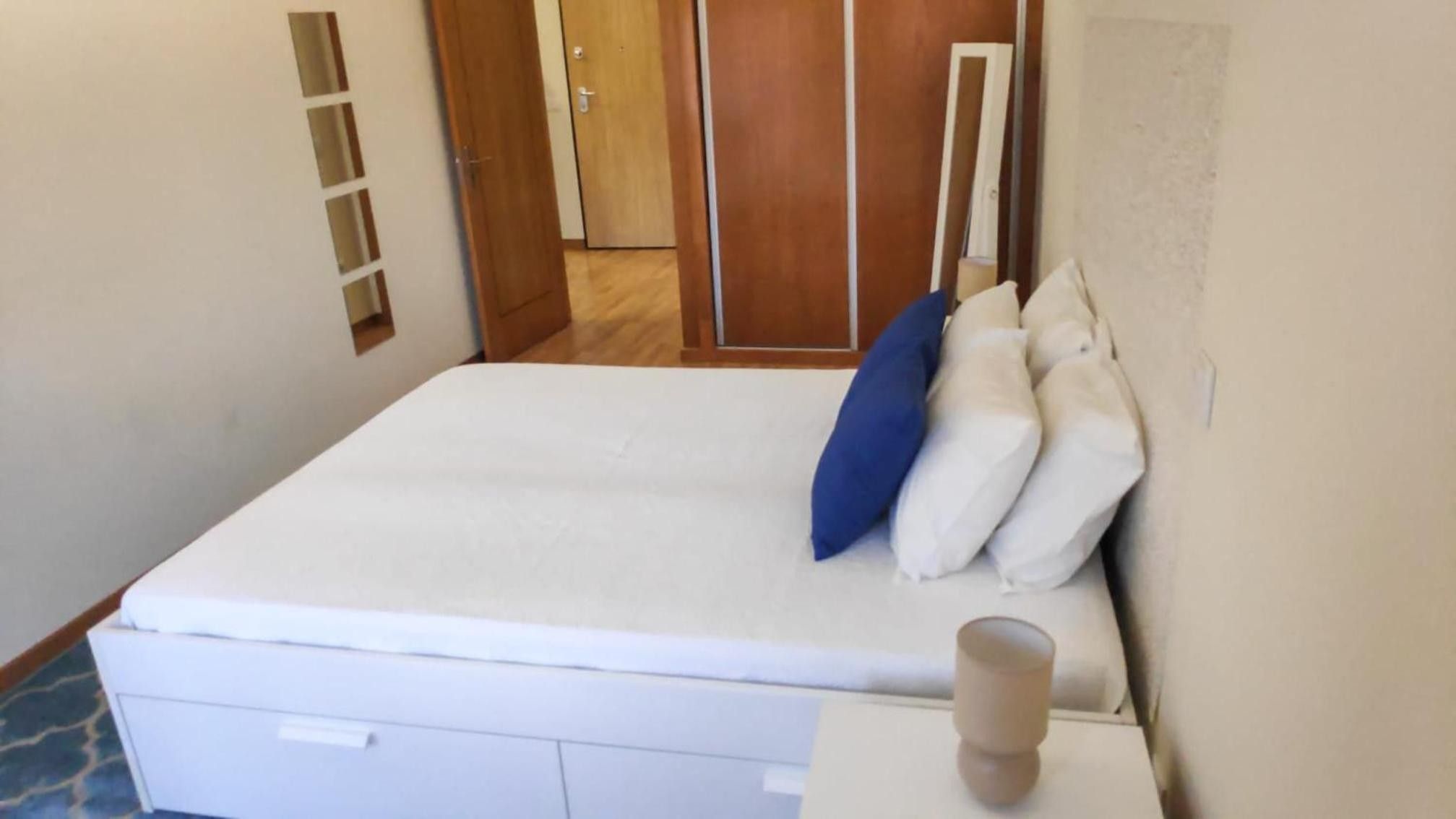Una habitación con una cama, una mesita de noche y una puerta que da a otra estancia.