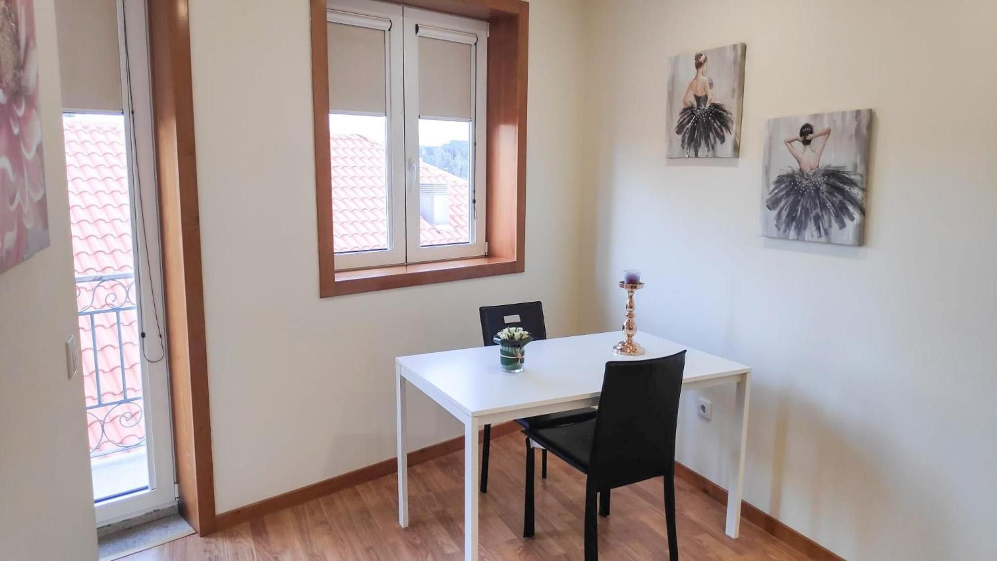 A small dining area with a white table, black chair, and a window with a view of buildings.