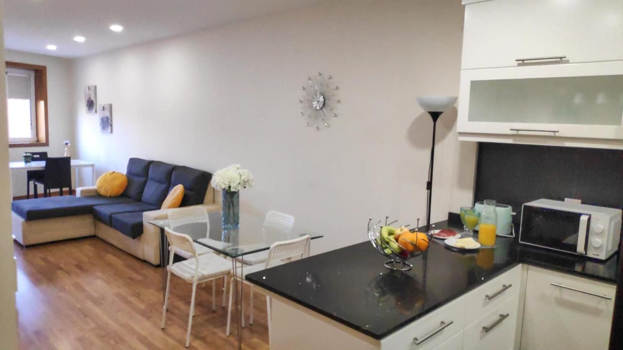 Un espacio habitable compacto con kitchenette, zona de comedor y área de descanso con sofá y sillas.