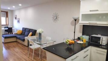 Un espacio habitable compacto con kitchenette, zona de comedor y área de descanso con sofá y sillas.