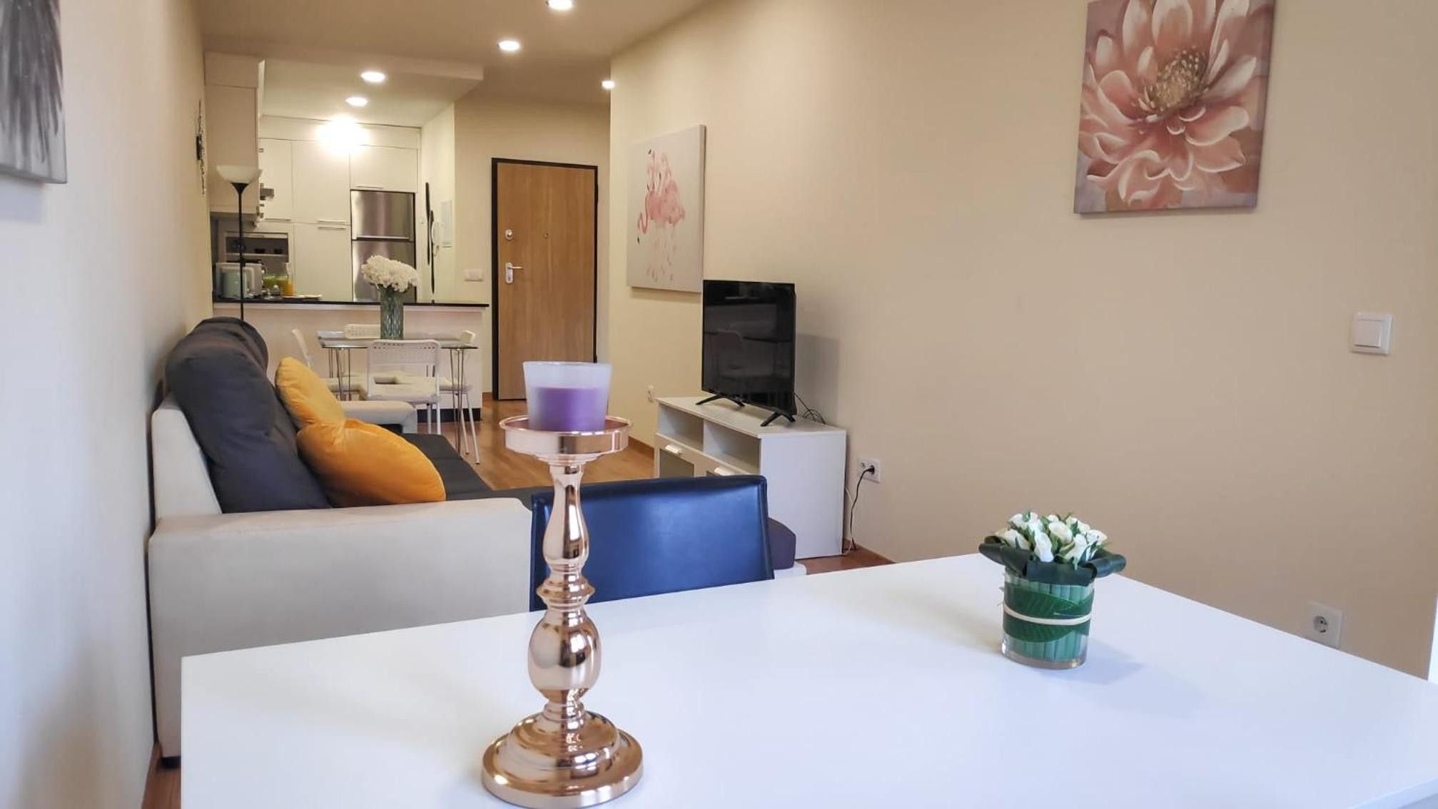 A modern living room with a white sofa, a coffee table, and a TV.