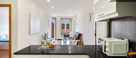 A modern kitchen with a black countertop, white cabinets, and a built-in microwave.