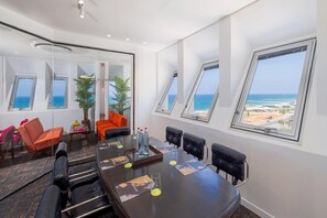 Een vergaderruimte met een grote tafel, zes stoelen en uitzicht op de oceaan door middel van dakramen.