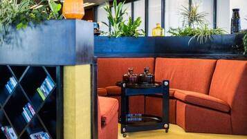 A modern interior with a sectional sofa, a small black cart with bottles, and a bookshelf with books.