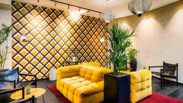 A modern interior with a yellow sofa set, black chairs, a red rug, and a geometric patterned wall.
