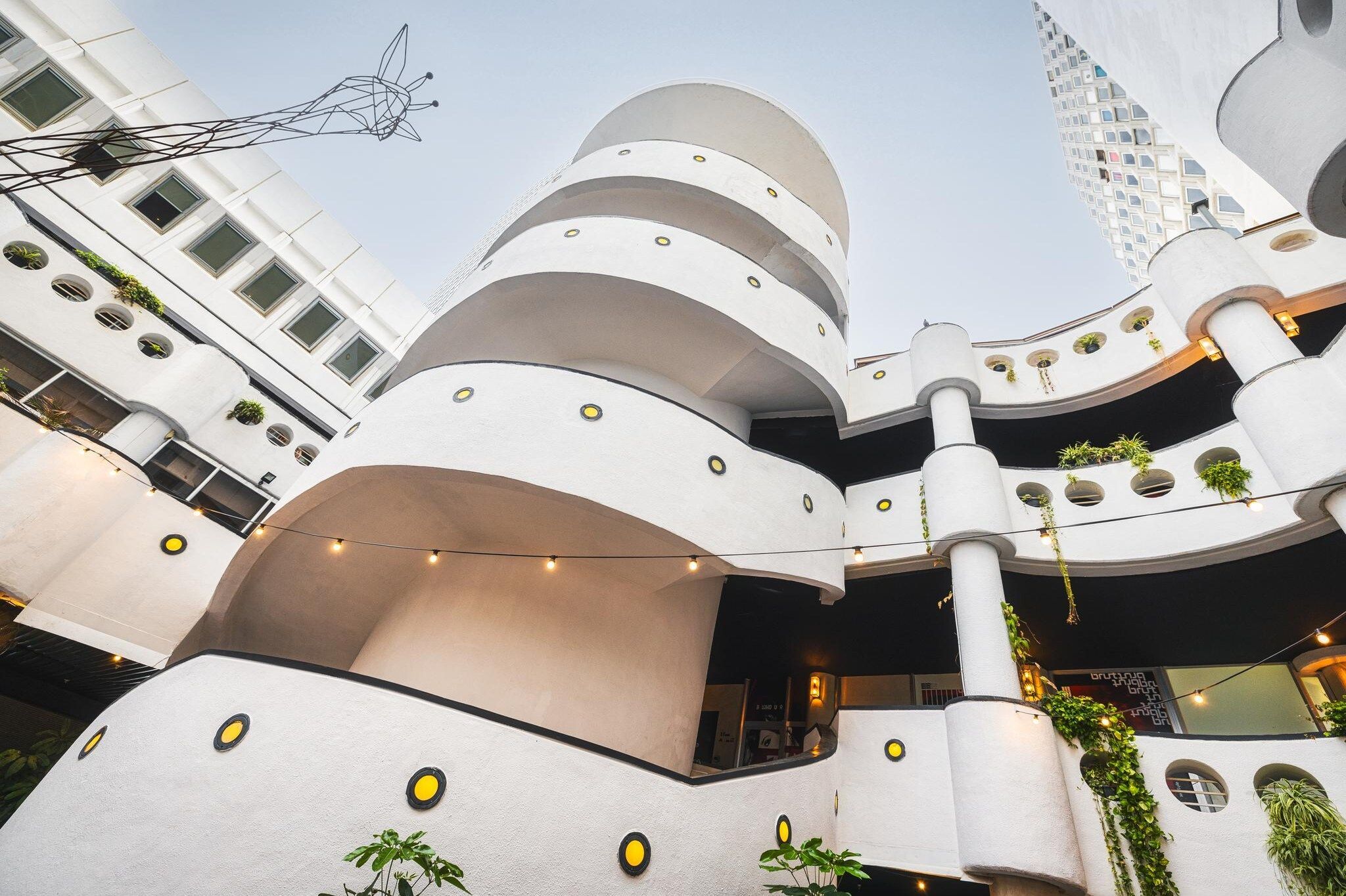 A multi-level building with balconies, outdoor lighting, and greenery.