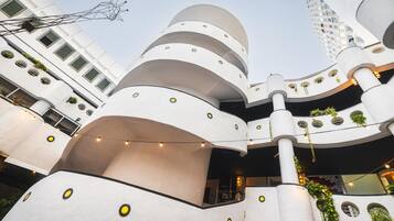 A multi-level building with balconies, outdoor lighting, and greenery.