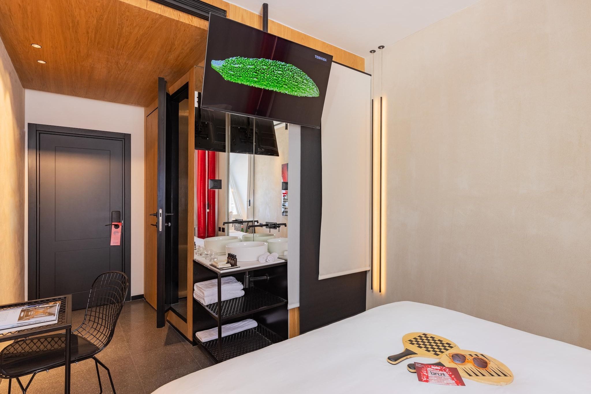 Una habitación de hotel con cama, escritorio, silla, armario y espejo.
