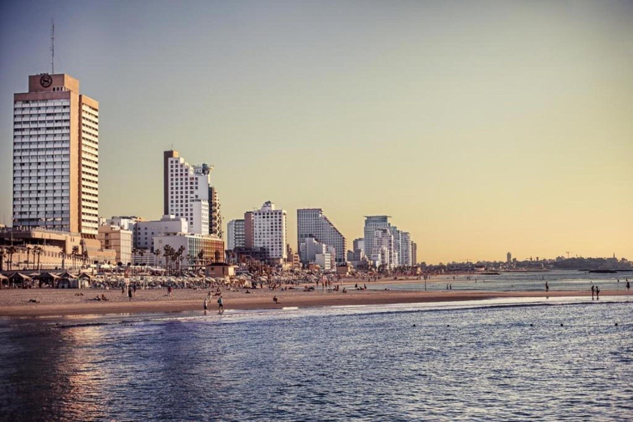 A coastal cityscape with high-rise buildings and a beach.