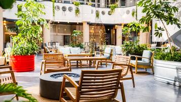 Un espace intérieur vaste et accueillant, doté de meubles en bois, d’un foyer central et de plantes en pot.