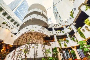 Un atrio de varios niveles con arquitectura moderna, que cuenta con balcones con plantas y luces colgantes.