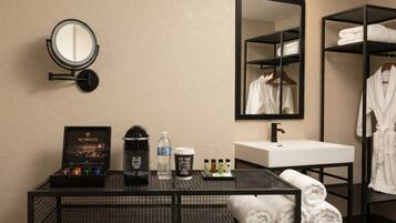 A hotel bathroom with a sink, mirror, and a rack of towels.