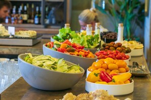 Een buffet met diverse gerechten, waaronder salades, fruit en groenten.