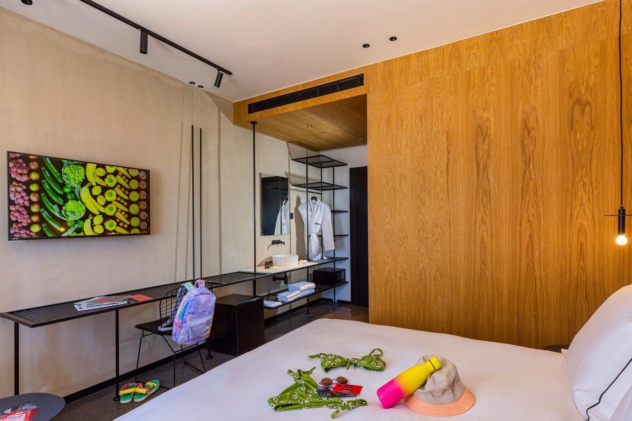 Une chambre d’hôtel moderne équipée d’un lit, d’un bureau, d’un miroir et d’un mur recouvert de panneaux en bois.