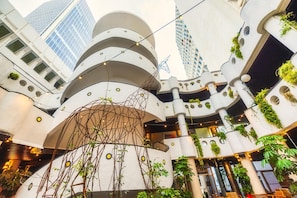 A multi-level atrium with modern architecture, featuring balconies with greenery and string lights. - Dancenter Brut Seafront Hotel Tel Aviv- Standard Single Room (Tel Aviv)