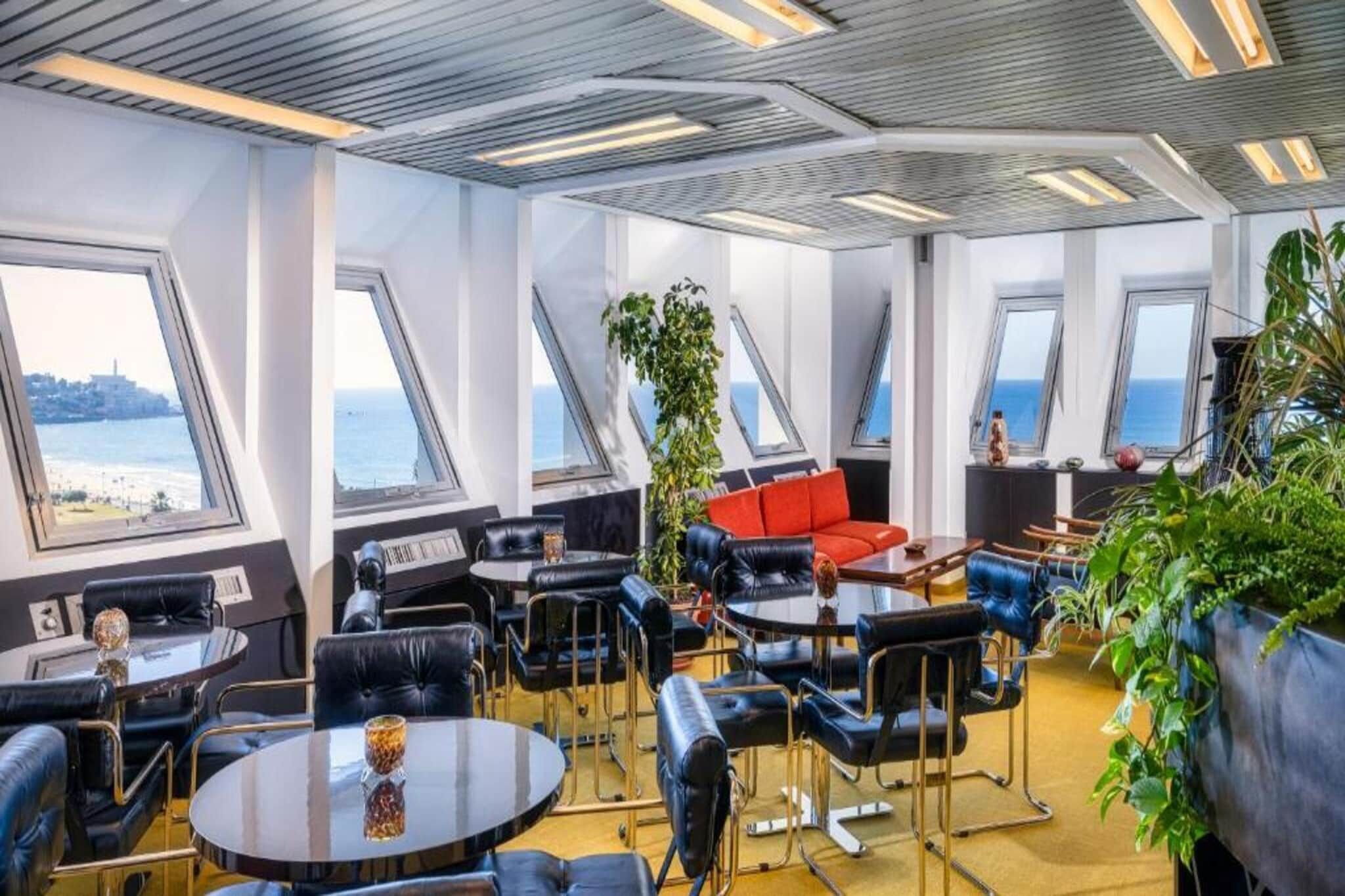 Een modern interieur met meerdere zithoeken, grote ramen en uitzicht op zee.
