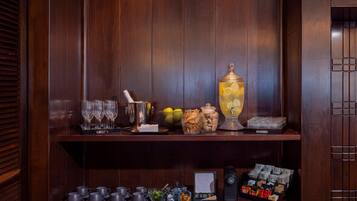 A wooden bar area with glasses, a cocktail shaker, a punch bowl, and various snacks.