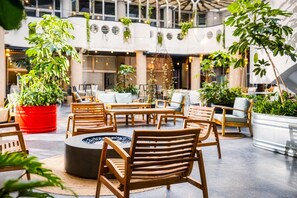 A spacious indoor area with wooden furniture, a central fire pit, and potted plants. - Brut Seafront Hotel by Sunday-Classic Double Room (Tel Aviv)