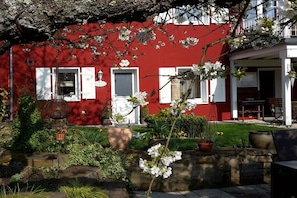 A red building with white shutters, a garden with potted plants, and a stone wall. - Apartment in Lohmar with swimming pool (Lohmar)