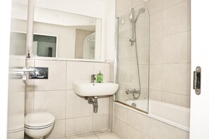 A bathroom with a toilet, a sink, a mirror, and a glass-enclosed shower. - Cozy Croydon Apartment Retreat (Croydon)