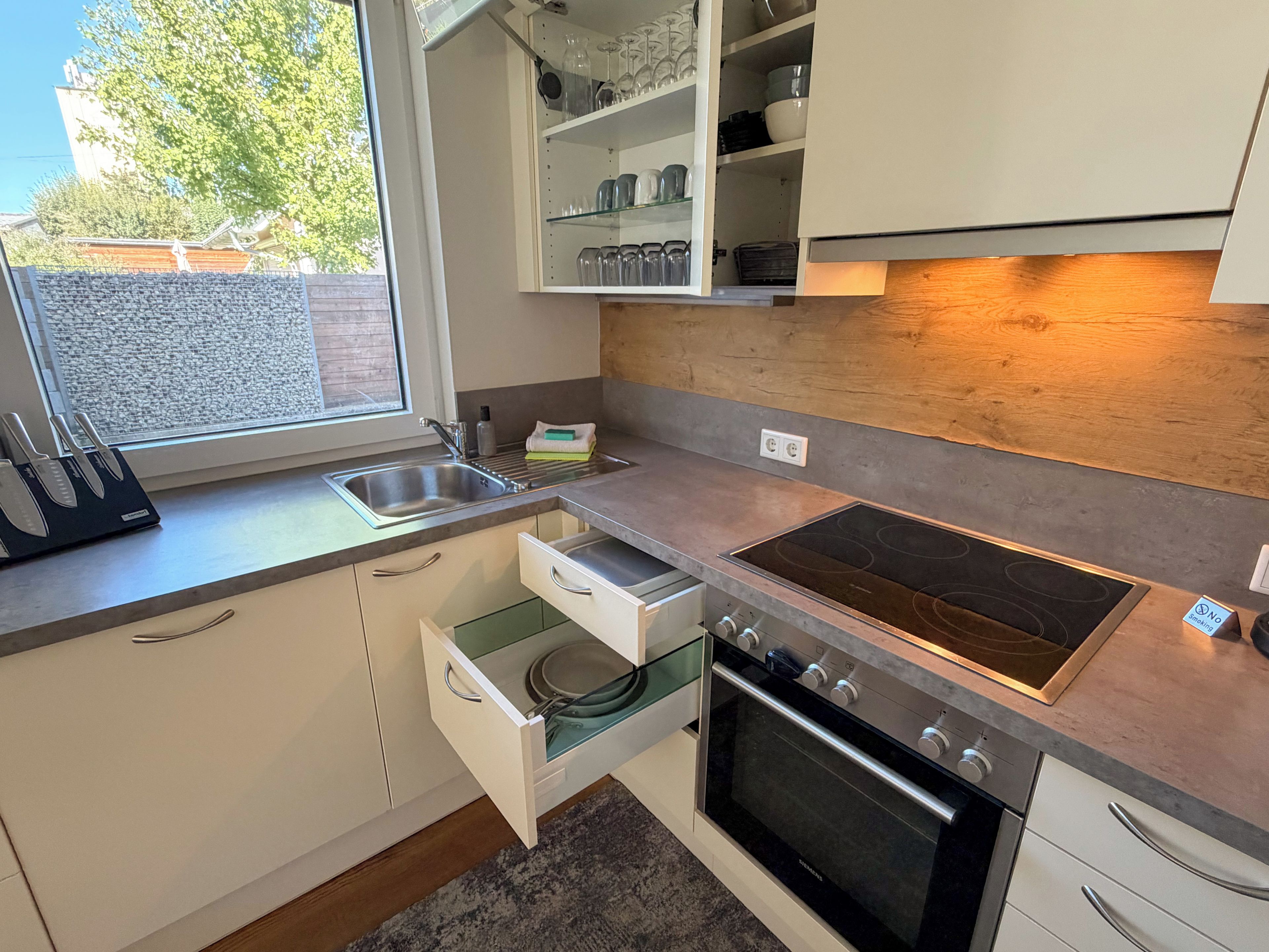 Una cocina moderna con horno empotrado, pileta de acero inoxidable y ventana con vista al exterior.