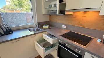 Una cocina moderna con horno empotrado, pileta de acero inoxidable y ventana con vista al exterior.
