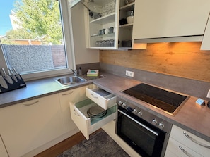 A modern kitchen with a built-in oven, a stainless steel sink, and a window providing a view of the outside. - Premium Apartment SIX, Stylish Apartment with a Garden and Terrace (Seekirchen am Wallersee)