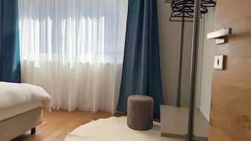 Ein Schlafzimmer mit einem Bett, einem runden Hocker, einer Stehlampe und einem Kleiderschrank.