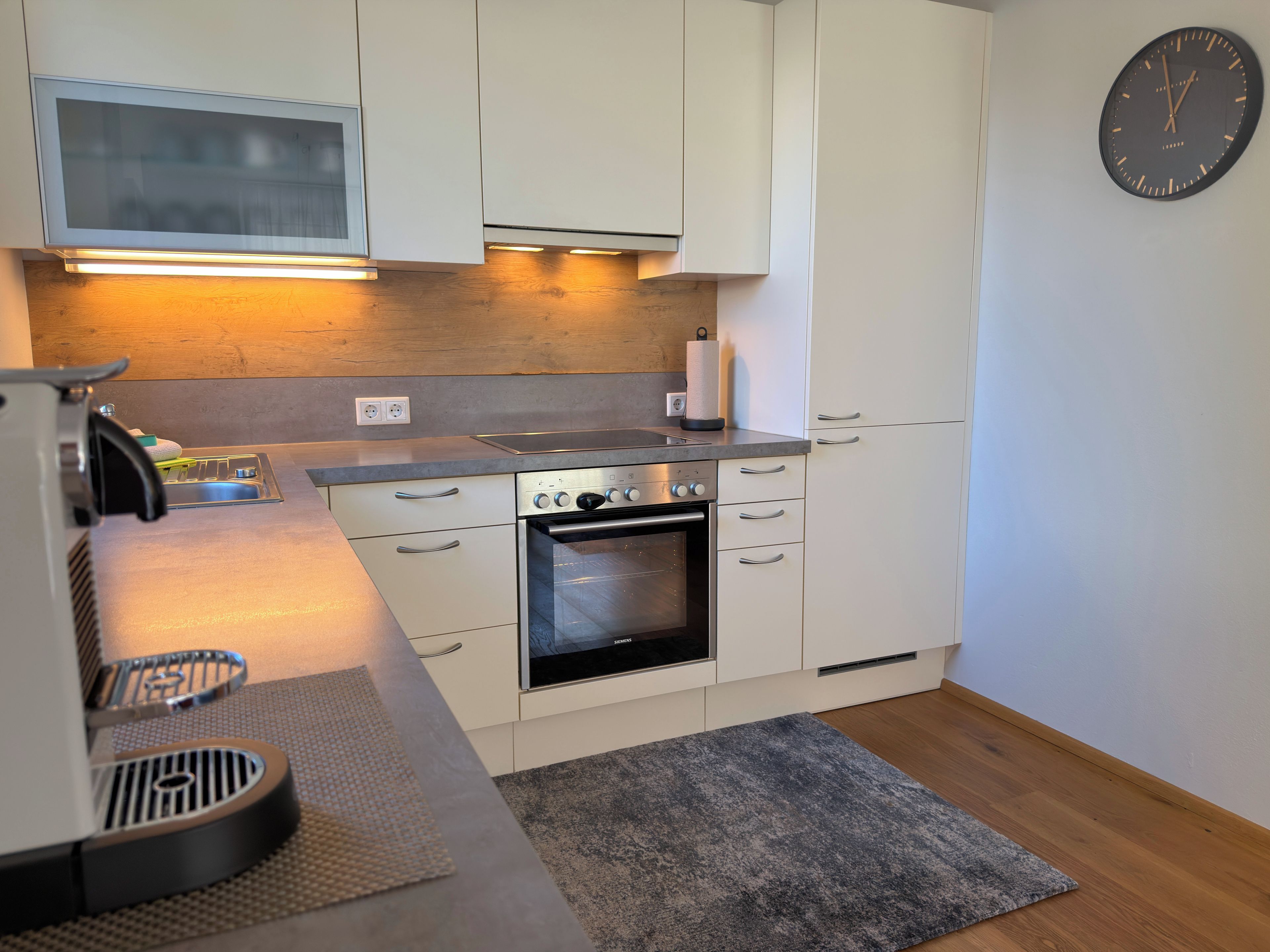 A modern kitchen with white cabinets, a built-in oven, and a microwave.