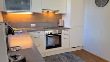 A modern kitchen with white cabinets, a built-in oven, and a microwave.
