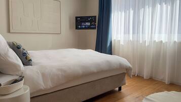 Een slaapkamer met een bed, een televisie en een raam met gordijnen.