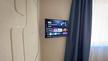A flat-screen TV mounted on a wall displaying a home screen with various streaming options.