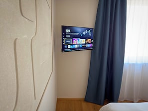 A flat-screen TV mounted on a wall displaying a home screen with various streaming options.