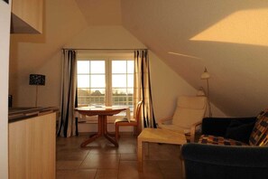 A cozy living room with a dining table, two chairs, a sofa, and a lamp. - The "Heligoland Upper Country" (Wurster Nordseeküste)