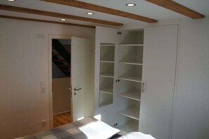 Ein Schlafzimmer mit einem Bett, einem Kleiderschrank und einer Tür zu einer Treppe.