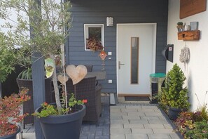 A residential exterior with a door, potted plants, outdoor furniture, and a small garden area. - Sigwart holiday apartment (Efringen-Kirchen)