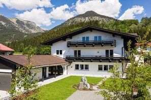 A two-story building with a balcony, a covered patio, and a mountain backdrop. - Holiday apartment in Oberstdorf with Wi-Fi (Oberstdorf)