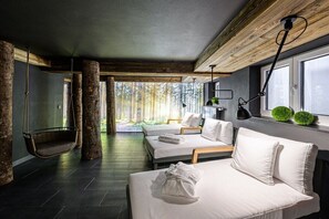 A modern hotel room with a large bed, a hanging chair, and a view of the forest. - Holiday apartment in Oberstdorf with Wi-Fi (Oberstdorf)