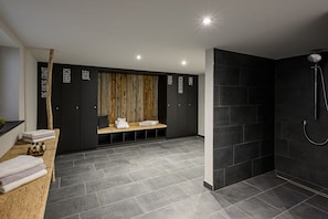 A modern bathroom with a shower, a bench with towels, and a wall with text. - Holiday apartment in Oberstdorf with Wi-Fi (Oberstdorf)