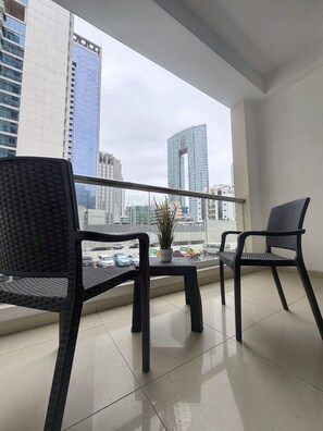 A balcony with two chairs, a small table, and a potted plant. - Bright 1BR in Dubai Marina with Balcony, Pool and Gym (Dubai)