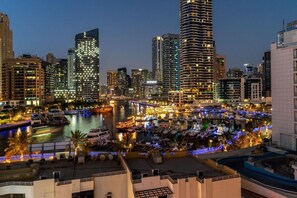 A cityscape with high-rise buildings, a marina with boats, and a waterfront promenade. - Bright 1BR in Dubai Marina with Balcony, Pool and Gym (Dubai)