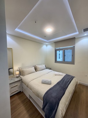 A bedroom with a bed, bedside table, lamp, and a window. - Bright 1BR in Dubai Marina with Balcony, Pool and Gym (Dubai)