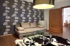 A living room with a sofa, a glass coffee table, a cowhide rug, and a door leading to another room. - Holiday apartment with 1 bedroom (Lindau (Bodensee))