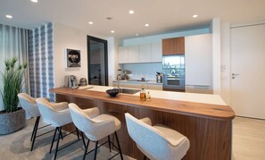 Una cocina moderna con una isla central, taburetes de bar y una planta en maceta.