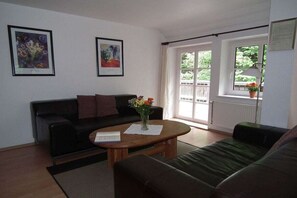 A living room with a black sofa, a wooden coffee table, and two framed artworks on the wall. - in the holiday home Nexö - 2 bedrooms (Ilsenburg)