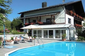 Ein Poolbereich mit Liegestühlen und einem Gebäude mit Balkon.