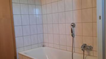 Kylpyhuone, jossa on kylpyamme, suihku ja pyyheteline.