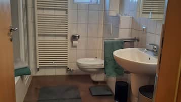 Et badeværelse med toilet, vask og et lille vindue.
