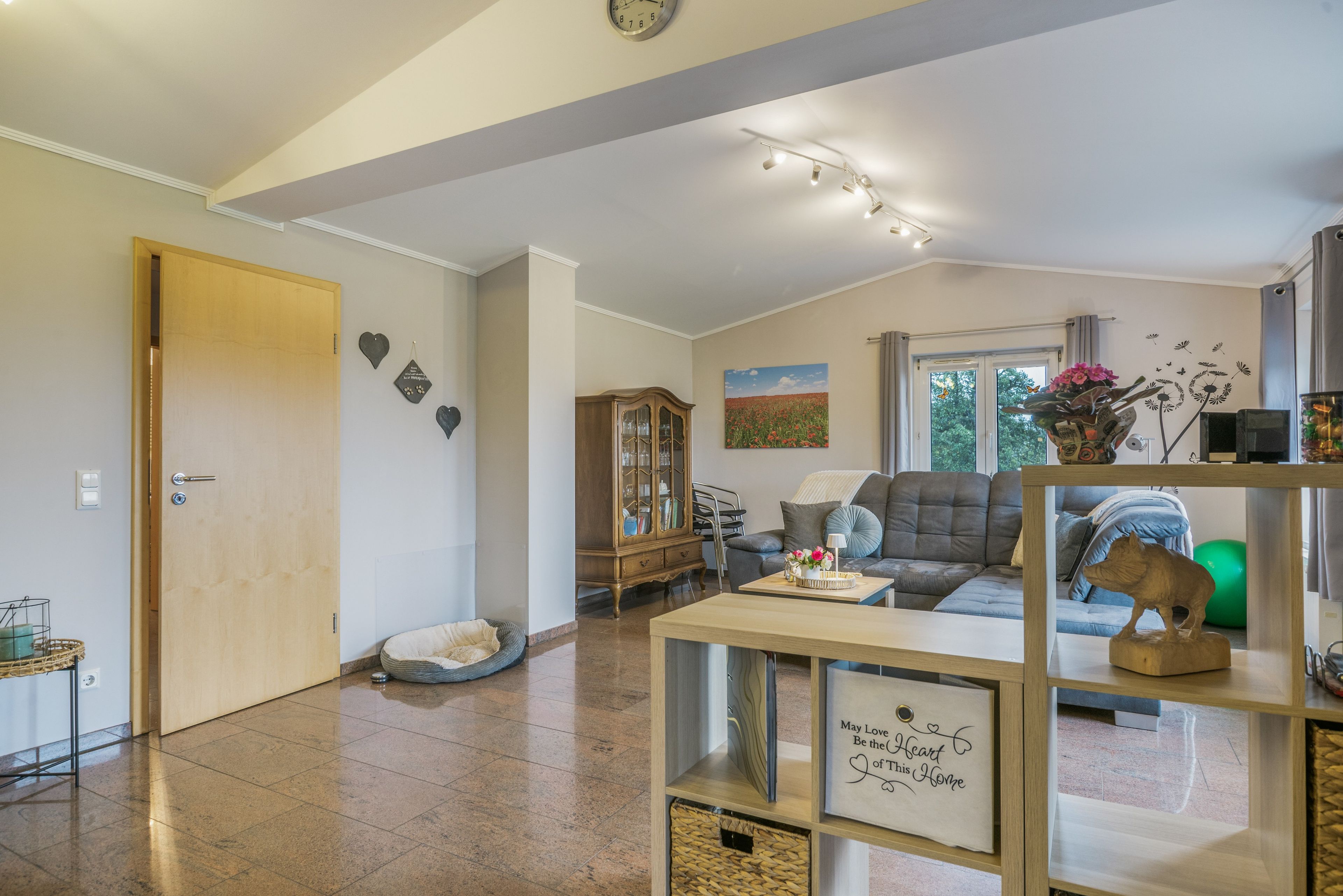 A spacious living room with a sofa, a wooden cabinet, and a decorative wall piece.