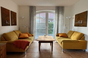 Un saló amb dos sofàs, una taula baixa i una finestra gran amb cortines.